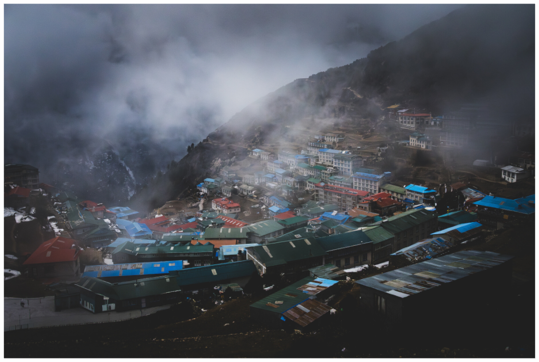 Namche Bazar im Himalaya, Nepal – Sherpa-Dorf mit bunten Dächern im Nebel, Fine Art Print von Daniel Lange.